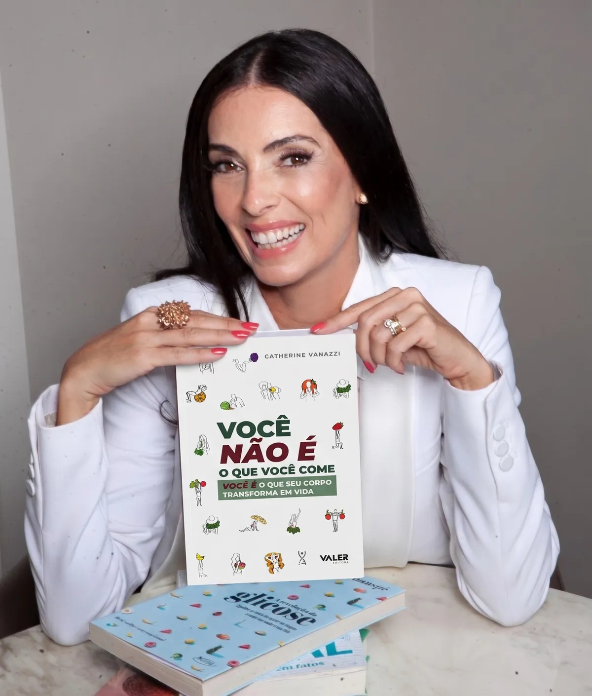 Catherine Vanazzi, nutricionista, sorrindo e segurando o livro dela, Você NÃO é o que você come